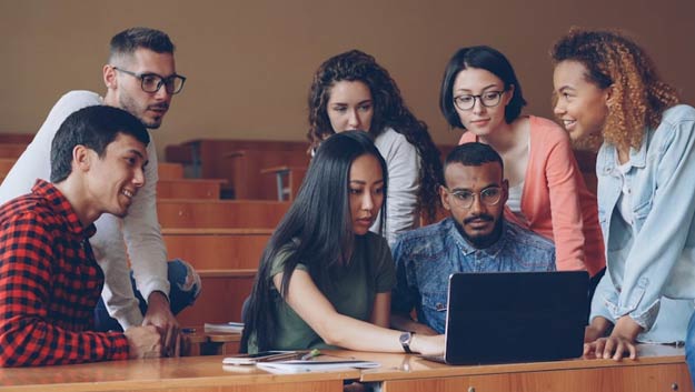 A group of business students and professionals collaborating on a digital project in a modern classroom
