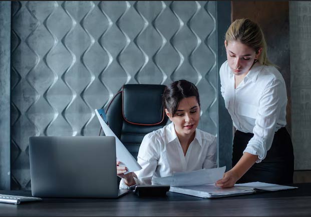 HR reviewing employee documents and paper files with a laptop