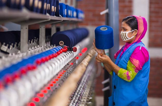 worker checking machinery output in a warehouse